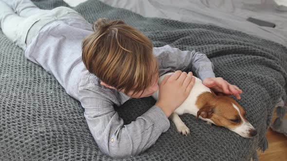 Boy cuddling his dog lying on bed