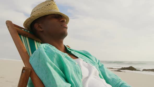 Side view of African american man sleeping in a sun lounger on the beach 4k