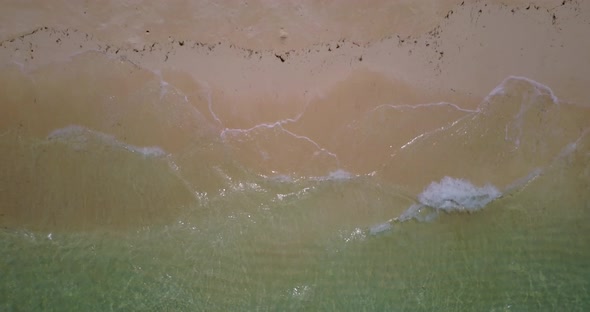 Wide above travel shot of a white sandy paradise beach and aqua blue water background