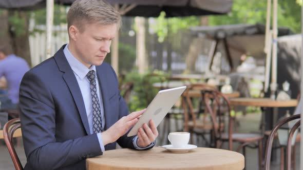 Businessman Using Tablet, Sitting in Outdoor Cafe