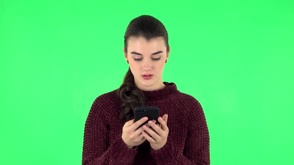 Young Smiling Woman Texting on Her Phone. Green Screen