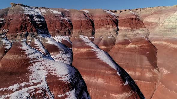 Aerial view flying over red dirt layers viewing color landscape in snow