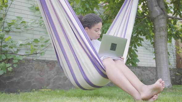 Face of Young African American Woman Sitting in the Hammock, Relaxing in the Garden