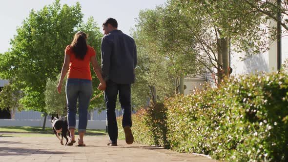 Happy caucasian couple is taking their dog for a walk