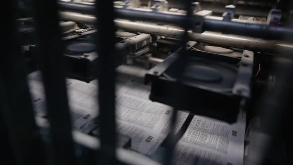 Printing House Machine Rotates Over Printed Newspaper