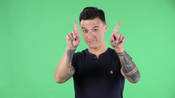 Portrait of a Handsome Young Guy Looking Straight Smiling and Showing a Heart Gesture and Air