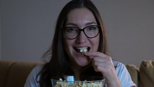 Woman in Glasses Eats Popcorn and Watches Television