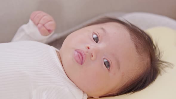 A happy newborn infant lying on a baby bed,smiling at the camera