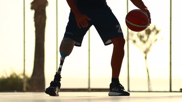 Man with Leg Prosthesis Playing Basketball in Tropical Sea Side at Sunset Time