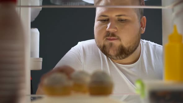 Overweight Man Opening Fridge and Eating Delicious Cream Cake at Night, Dieting