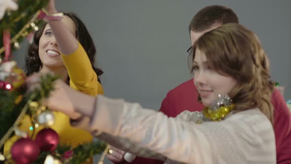 Friendly Family Joyfully Decorating Christmas Tree on Eve of Bright Holiday