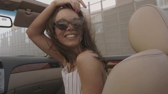 Young beautiful and smiling hipster girl in convertible car