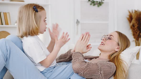 Portrait Cheerful Mother Older Sister Babysitter Lies on Sofa at Home Playing Patty Cake Game with