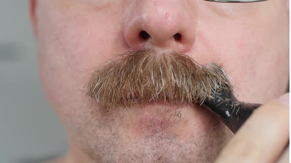 Man shaving off his mustache with an electric razor. Facial Hair Trimmer. Close Up