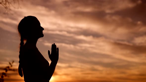Silhouette of a woman praying with Amazing dramatic sky sunset background.