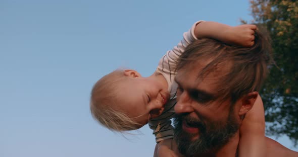 Smiling Baby Boy Sits on Father Neck and Have Fun Together Outdoor in Sunset