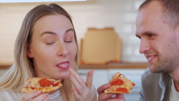 A Young Couple Is Having Lunch in the Living Room. Eating Pizza