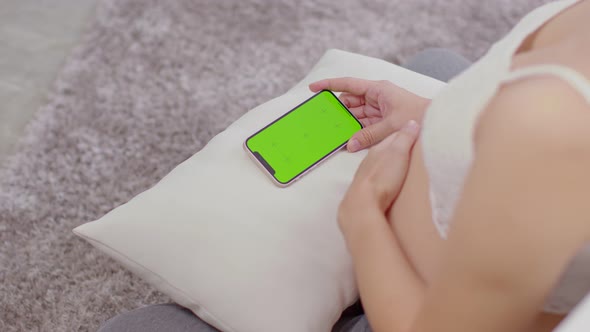 Close up hand of pregnant woman holding mobile phone with green screen or chroma key