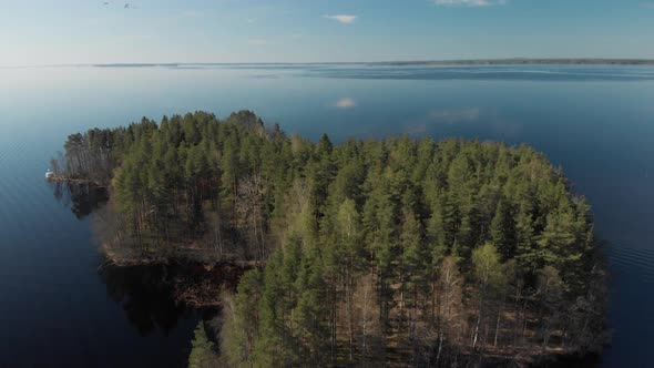 Drone flight over a small island covered by a thick forest