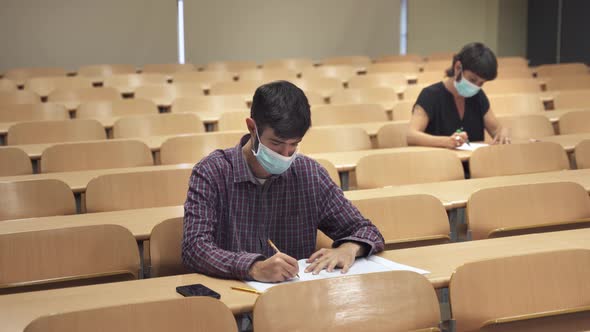 College students wearing face masks attend lecture at University and take exam