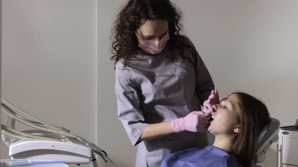 Orthodontist using dental impression tray on woman teeth