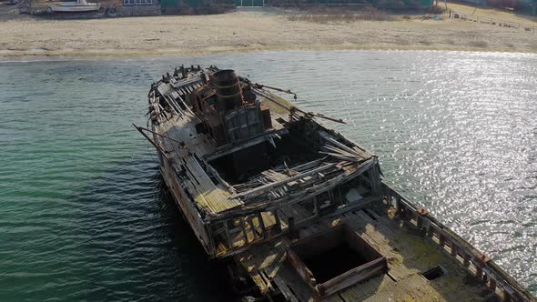 A Wrecked Wooden Ship Lies on the Seashore Covered with Rust