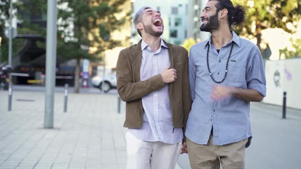 Happy Gay Couple Having Fun Talking and Walking Together Holding Hands in the City