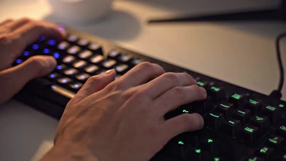 Male hands typing on a gaming RGB keyboard.