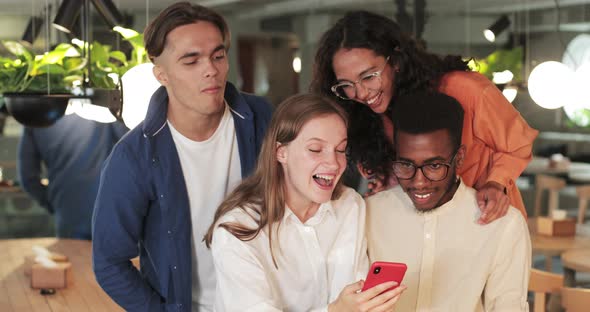 Group of Cheerful People Laughing While Looking at Smartphone Screen. Happy Friends Viewing Photos