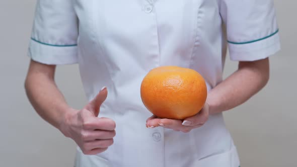 Nutritionist Doctor Healthy Lifestyle Concept - Holding Grapefruit and Medicine or Vitamin Pill