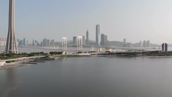 Drone backwards reveal shot showing traffic on Sai Van Bridge with base of Macau Tower