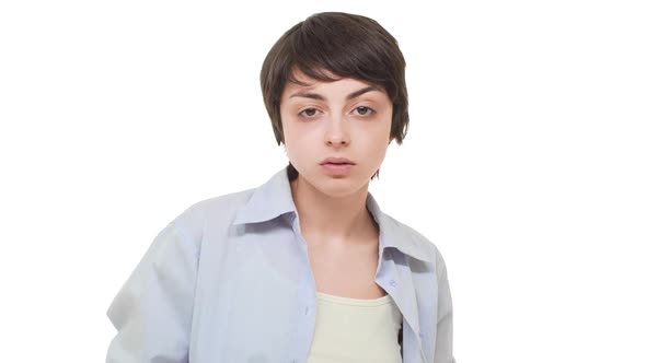 Arrogant Young Caucasian Female Standing Over White Background Chewing Gum and Staring at Camera in