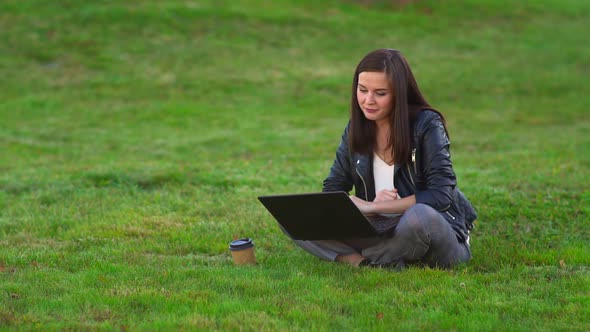 Young Girl in the Park with a Laptop. Talking on Video Call