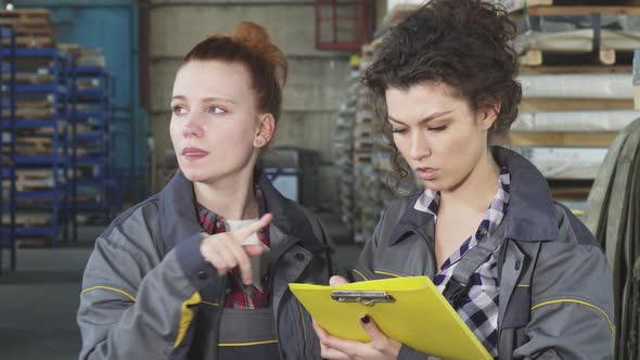 Attractive Female Engineer Talking To Her Colleague at the Factory Warehouse