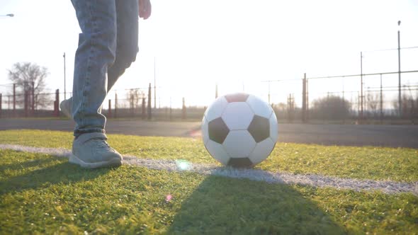 A Child Girl Playing with Soccer Ball Under Sun Light. Green Field in City Park at Sunny Day. Action