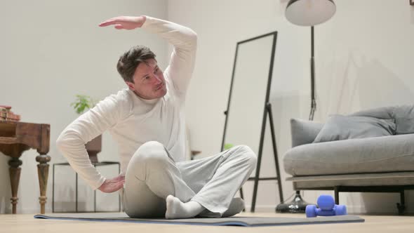 Middle Aged Man Doing Stretches on Yoga Mat at Home