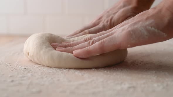 Camera follows man’s hands kneading a dough. Slow Motion.