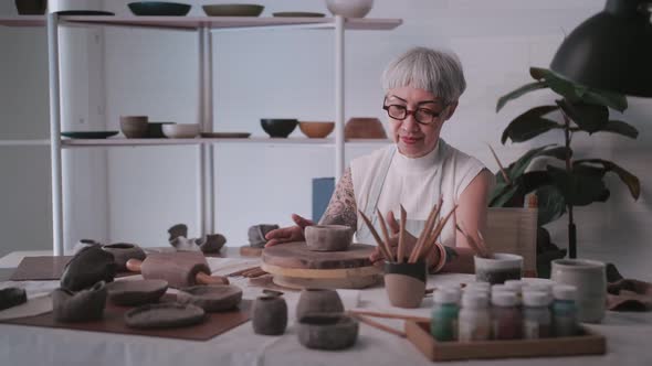 Asian elderly woman enjoying pottery work at home.