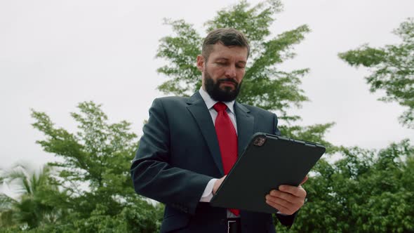 Portrait of a Serious Business Man Bearded Businessman in an Expensive Suit in a Red Tie Working on