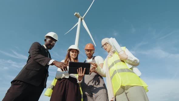 Group of Four Multiracial Coworkers in Safety Helmets Smiling on Camera While