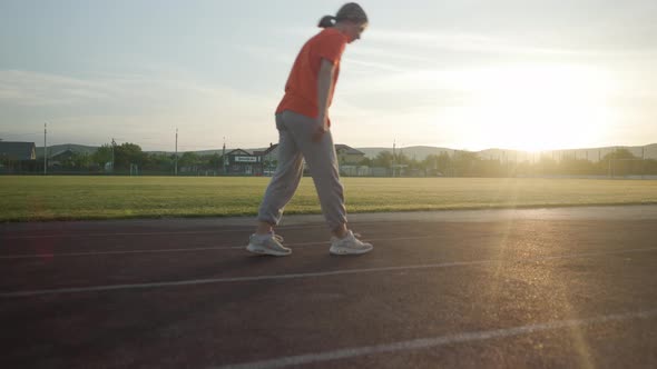 Young Beautiful Girl in Sweatpants and an Orange Tshirt Goes in for Sports