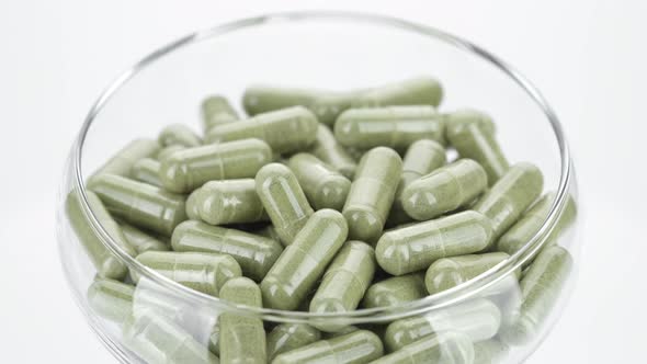 super food moringa capsules in clear bowl, rotation. Spirulina, chlorella capsules