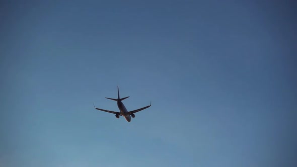 Silhouette of Plane Flying Through Evening Sky. Fast Airplane Departing To Place of Destination in