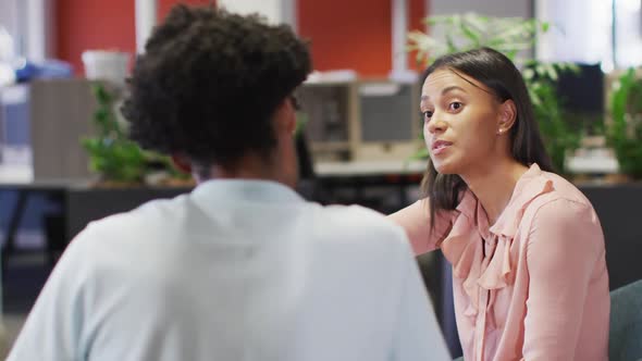 Video of focused diverse businesswoman and businessman using tablet and talking