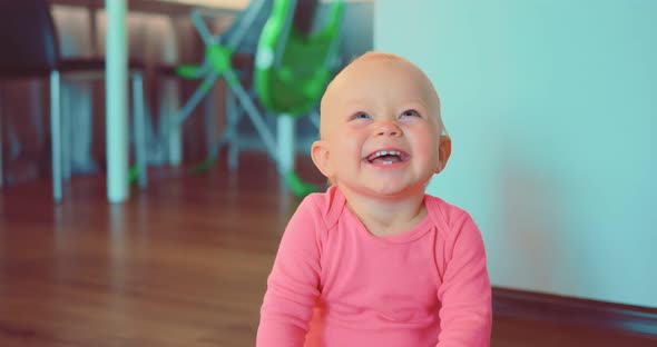 Smiling Cute Little Girl Sitting on Floor of House in Room