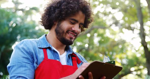 Gardener thinking and writing on clipboard