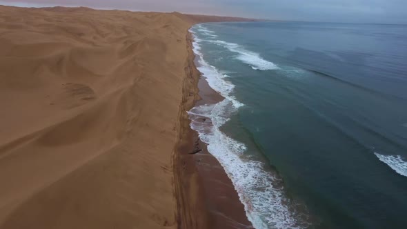 Drone shot of Sandwich Harbour in Namibia - drone is following the coastline where desert meets the