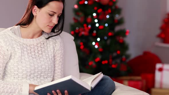 Pretty brunette reading book at christmas time