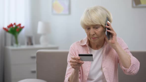 Confused Senior Woman With Credit Card Calling Bank Support, Online Fraud Victim