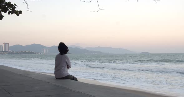 An Aged Woman Wearing a Protective Mask Is Doing Exercises and the Sea View Wearing a Covid19 Mask